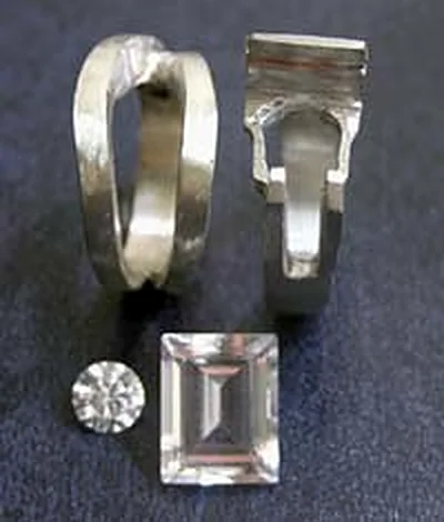 A round brilliant diamond and an emerald-cut stone beside two white gold ring mountings