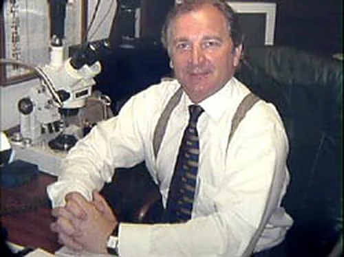 Walter Zimochod at his desk, with the workshop microscope behind him